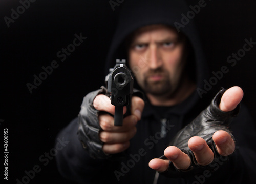 Photo: Robber with gun holding out hand Robber with gun holding out hand