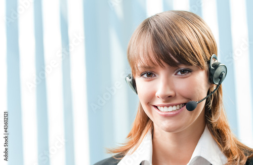 Photo: Cheerful smiling support phone operator at office Cheerful smiling support phone operator at office