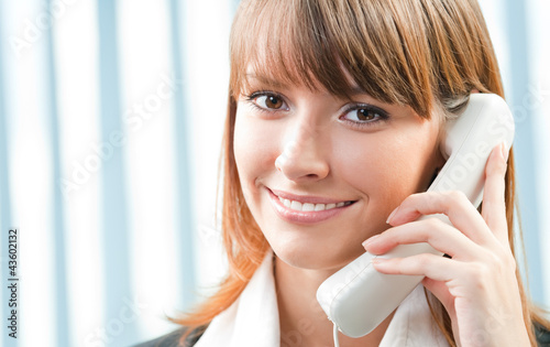 Foto: Young business woman with phone at office Young business woman with phone at office