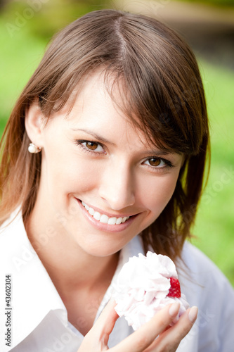 Foto: Portrait of young woman with cake outdoors Portrait of young woman with cake outdoors