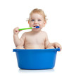 Happy baby kid brushing teeth sitting in basin