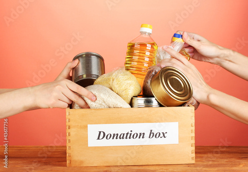 Photo: Donation box with food on red background close-up Donation box with food on red background close-up