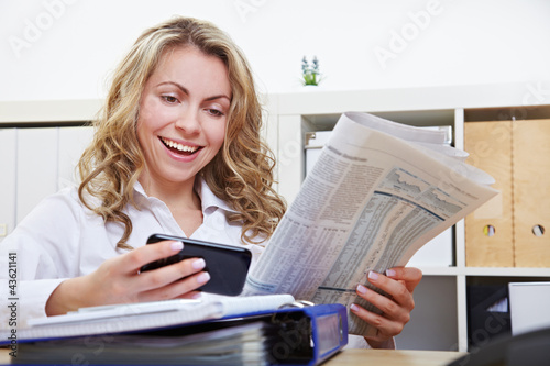 Photo: Frau mit Smartphone liest Zeitung Frau mit Smartphone liest Zeitung