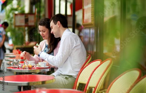 Photo: Happy couple eating macaroons in a Parisian outdoor cafe Happy couple eating macaroons in a Parisian outdoor cafe
