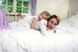 A girl lying on the bed hugging her mother from the back