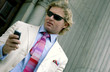 A man in business suit and colourful tie text messaging on his hand phone                               