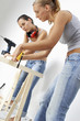 A woman helping her friend to measure a wood