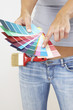 A woman in jeans pointing at the selected colour from the colour cards