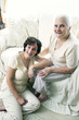 A woman sitting on the floor while her old mother is sitting on the couch
