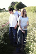 A guy and a lady picking flowers with their parents following behind
