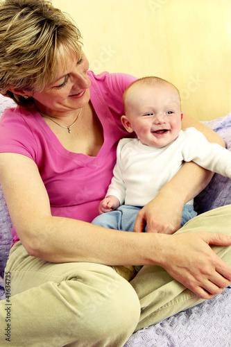 Photo: A baby boy smiling happily sitting on his mother's lap A baby boy smiling happily sitting on his mother's lap