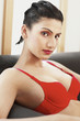 A lady in red bra sitting on a black couch