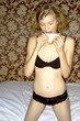 A woman in black lingerie kneeling on the bed eating sandwich