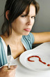 Woman with angry face sitting in front of a question marked plate