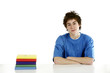 Boy sitting beside a stack of books