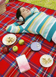 Woman listening to music on the headphones while picnicking in the park