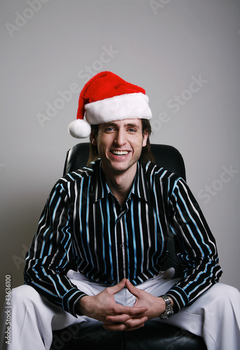 Photo: Businessman in Christmas hat smiling at the camera Businessman in Christmas hat smiling at the camera