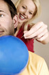 Woman trying to poke on balloon with a needle