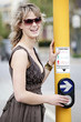 A teenage girl pressing the traffic light button for pedestrian passing
