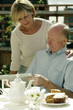 Husband and wife reading newspaper while having breakfast