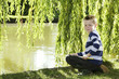 Photo: Young boy sitting by the lake side holding fishing net Young boy sitting by the lake side holding fishing net