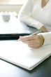 Businesswoman writing on a book while using laptop