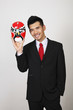 Businessman holding up a Chinese mask
