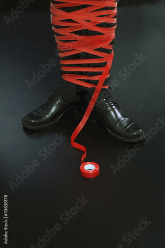 Photo: Businessman tied up in red tape Businessman tied up in red tape