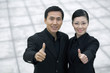 Businessman and businesswoman showing thumbs up