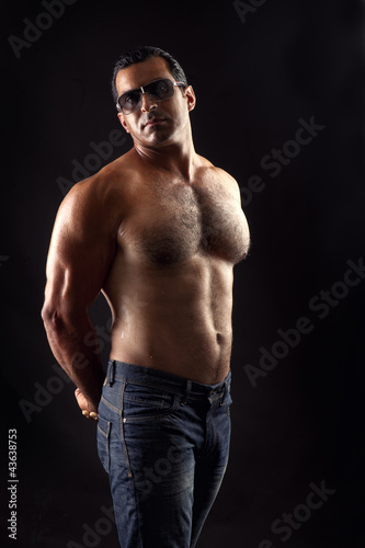Foto: portrait of topless athletic man posing over black background portrait of topless athletic man posing over black background