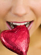 Woman biting a heart-shaped chocolate