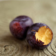Close up of a bitten plum next to another plum