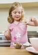 Girl pouring flour mixture on cupcakes
