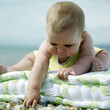 Baby girl sitting on cushion playing with pebbles