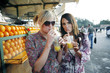 Women enjoying fresh orange juice at beverage stall