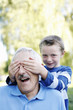 Boy covering his grandfather's eyes