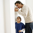 Boy watching his father fixing the wall