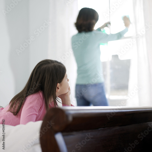 Photo: Girl watching her mother cleaning the window Girl watching her mother cleaning the window