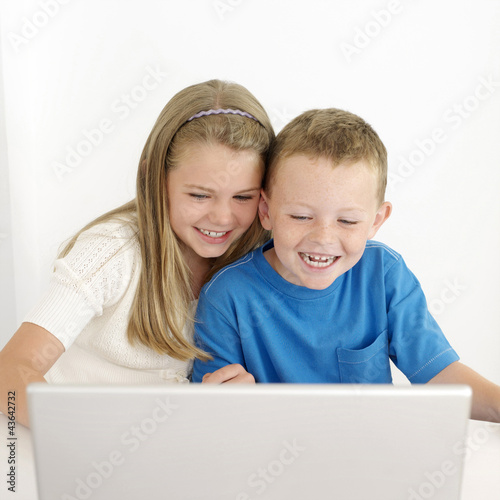 Photo: Boy and girl laughing while using laptop Boy and girl laughing while using laptop
