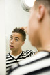 Boy looking at the mirror, styling his hair