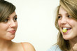 Girl with grape in her mouth, another girl watching