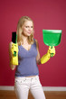 Woman with rubber gloves holding a hand broom and dust pan