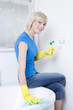 Woman with rubber gloves, cleaning the bathtub