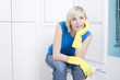 Woman with rubber gloves sitting on the toilet bowl