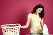 Woman looking at iron while holding onto a laundry basket
