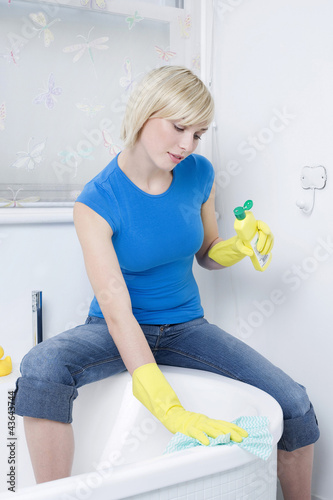 Photo: Woman with rubber gloves, cleaning the bathtub Woman with rubber gloves, cleaning the bathtub