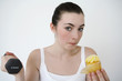 Woman eating cupcake while lifting dumbbell