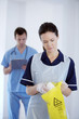 Nurse disposing waste with doctor in the background