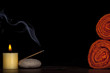 Spa concept - towels, candle and incense stick over black