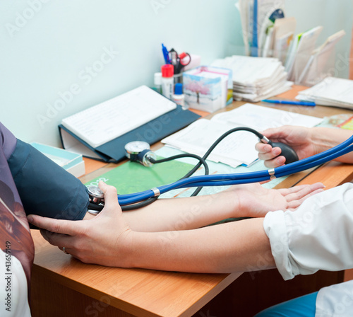 Photo: doctor takes blood pressure doctor takes blood pressure
